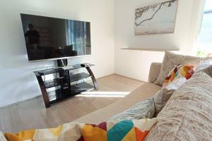 ein Wohnzimmer mit einem Sofa und einem Flachbild-TV in der Unterkunft New and Cozy 2 Bedrooms Granny Flat with Aircon & Pool in Baulkham Hills