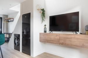 sala de estar con TV de pantalla plana en la pared en Luxury fully equipped studio - centrally located, en Huizen