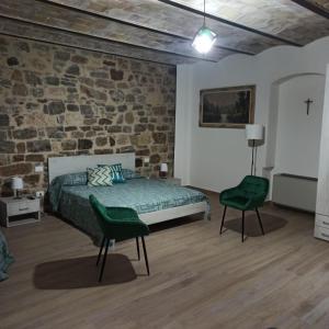 a bedroom with a bed and two green chairs at Dream House Castellana in Castellana Sicula