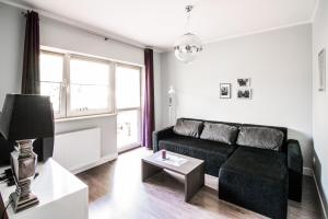 sala de estar con sofá negro y mesa en Apartamenty Algador, en Cracovia