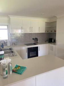 a kitchen with white cabinets and a counter top at OAK FLATS - Cosy Getaway in Lake Illawarra