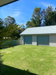 a garage with a grass yard in front of it at OAK FLATS - Cosy Getaway in Lake Illawarra