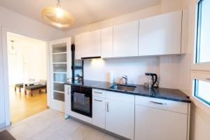a kitchen with white cabinets and a black counter top at Loving apartment right in the heart of Zurich! in Zurich