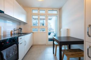 a kitchen with white cabinets and a table and a window at Loving apartment right in the heart of Zurich! in Zurich