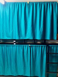 - un rideau bleu dans une pièce avec une échelle dans l'établissement Black Pantera Hostel, à Patong Beach