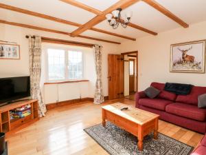 uma sala de estar com um sofá vermelho e uma mesa de centro em Twyford Farm Cottage em Tiverton