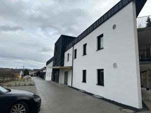 un bâtiment blanc avec une voiture garée à côté dans l'établissement GreenLeaf Regensburg I Sinzing, à Sinzing