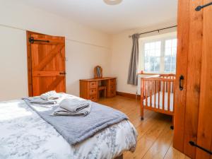 a bedroom with a bed and a crib and a window at Twyford Farm Cottage in Tiverton