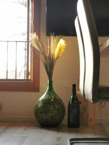 Un jarrón verde con una planta al lado de dos botellas en Luxury Home, en Codognè