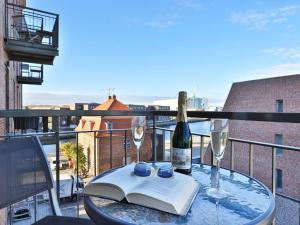 ein Glastisch mit einem Buch und Weingläsern auf einem Balkon in der Unterkunft Ohlerich Speicher App. 21 in Wismar