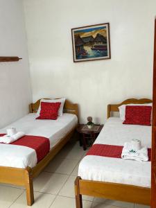una camera con due letti con lenzuola rosse e bianche di Hospedaje Casa Amazónica Iquitos a Iquitos
