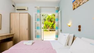 a bedroom with a pink and white bed and a window at Marina Apartments in Agios Gordios