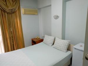 a small bedroom with a white bed with two pillows at Begumhan Pansiyon in Antalya
