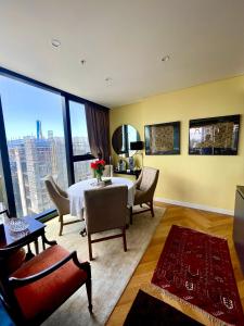 - un salon avec une table, des chaises et une grande fenêtre dans l'établissement Sydney Cosmopolitan CBD Apartment, à Sydney