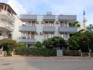un edificio de apartamentos blanco con una torre en el fondo en Begumhan Pansiyon, en Antalya