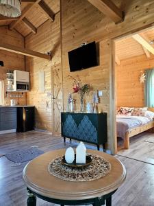 Cabaña de madera con sala de estar con cama y mesa. en Domek Polna Cisza Bieszczady en Lesko