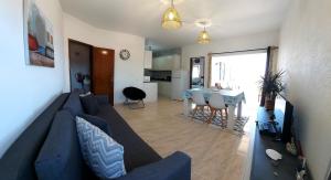 a living room with a blue couch and a kitchen at Sunset View Flat in Aljezur