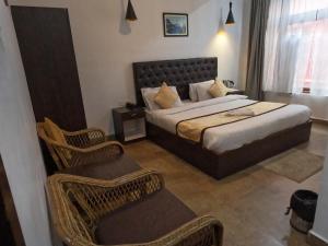 um quarto com uma cama e 2 cadeiras de vime em Hotel Rainbow em Gangtok