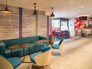 une salle d'attente avec un canapé vert et des chaises dans l'établissement Hotel ibis Narbonne, à Narbonne