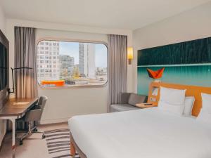 a hotel room with a bed and a desk and a window at Novotel Paris Centre Tour Eiffel in Paris