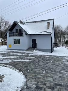 une maison blanche avec de la neige sur le toit dans l'établissement Nad Potokiem, à Wapienne