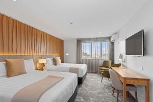 a hotel room with two beds and a flat screen tv at Hotel Elms Christchurch, Ascend Hotel Collection in Christchurch