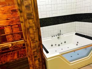 a bath tub in a bathroom with black and white tiles at Apartamenty Toskania No.4 Jacuzzi & Sauna in Poznań