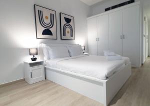 a white bedroom with a large white bed and cabinets at 1min walk studio in front of JBR beach in Dubai