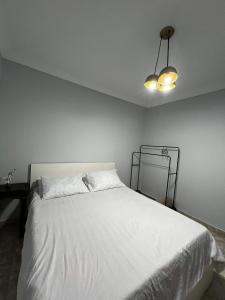 ein Schlafzimmer mit einem weißen Bett und einer Lampe in der Unterkunft Corniche Glimpse in Alexandria
