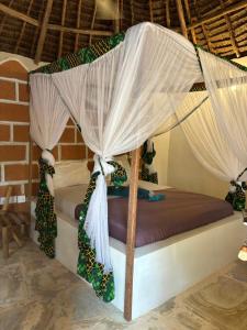 a bedroom with a bed with a canopy at Dreamland Bungalows Michamvi Kae in Michamvi