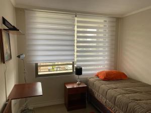 - une chambre avec un lit et une fenêtre avec des stores dans l'établissement Hermoso y cómodo departamento en el centro de Viña del Mar - Viña Park 2, à Viña del Mar