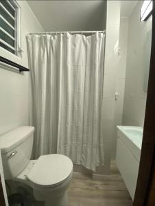 y baño con aseo y cortina de ducha. en Verdemar Apts, en San Juan