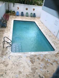 einen Pool mit Steinboden und blauen Stühlen in der Unterkunft Verdemar Apts in San Juan