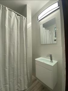 ein weißes Badezimmer mit einem Waschbecken und einem Spiegel in der Unterkunft Verdemar Apts in San Juan