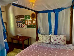 a bedroom with a canopy bed and a table at Milele Lodge in Michamvi