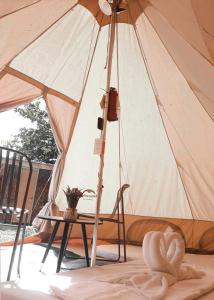a tent with a chair and a table with an umbrella at JUSH NATIVE AND GLAMPING in Dauis