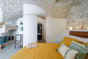 a bedroom with a yellow bed and a stone wall at Gattoni Room by Rentbeat in Martina Franca