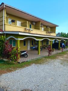 une maison jaune avec une terrasse en face de celle-ci dans l'établissement NURUL ROOMSTAY LANGKAWI, à Pantai Cenang