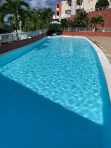 a swimming pool in a hotel with blue water at Studio Martinique Ti Family in La Trinité