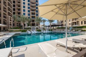 a swimming pool with chairs and an umbrella at Chic 2 Beds With Pool View Asayel B3 MJL in Dubai