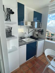 a kitchen with blue and white cabinets and a sink at Studio Martinique Ti Family in La Trinité