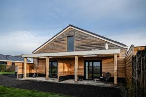 a wooden house with a front porch and windows at B&B de Cley in Noordwijk