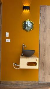 a bathroom with a sink on a yellow wall at Corinto Tiny House in Paipa