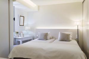 1 dormitorio blanco con 2 camas y mesa en Apartamentos do Mar - Pikis Flat, en Funchal