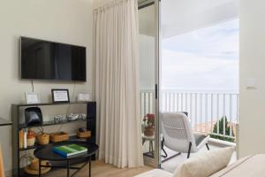 sala de estar con TV, mesa y balcón en Apartamentos do Mar - Pikis Flat, en Funchal