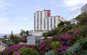 un alto edificio blanco en una colina con flores púrpuras en Apartamentos do Mar - Pikis Flat, en Funchal