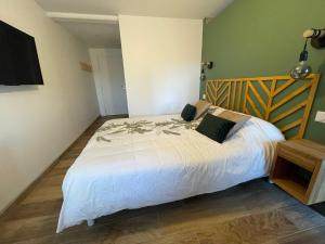 a bedroom with a large white bed with a wooden headboard at Chez Gabriel et Sophie in Pérouges