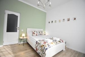 a white bedroom with a bed and a chandelier at Homey Luxury- entire house, free parking, yard in Cluj-Napoca