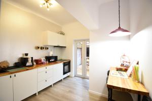 a kitchen with white cabinets and a wooden table at Homey Luxury- entire house, free parking, yard in Cluj-Napoca