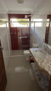 a bathroom with a shower and a toilet and a sink at Recanto Ville House in Porto Seguro